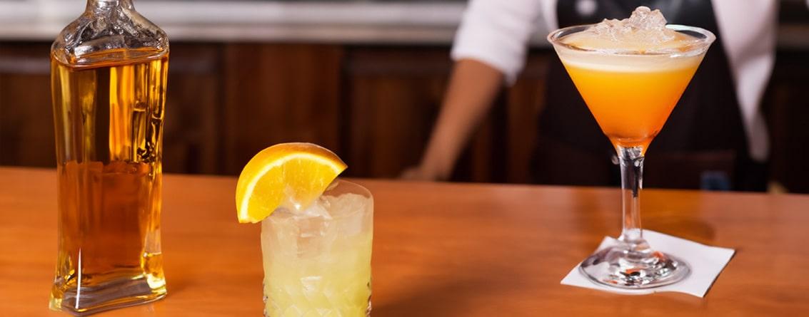Comptoir avec des cocktails et un barman en arrière plan
