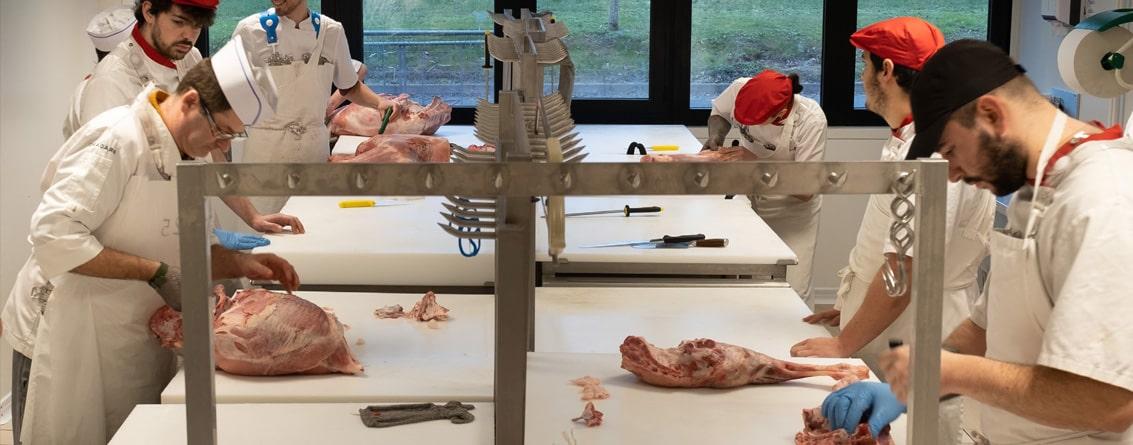 Apprentis boucher en laboratoire en train de travailler avec leur professeur sur le désossage 