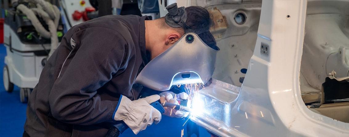 Apprenti carrossier réalisant une soudure sur la carrosserie d'une voiture