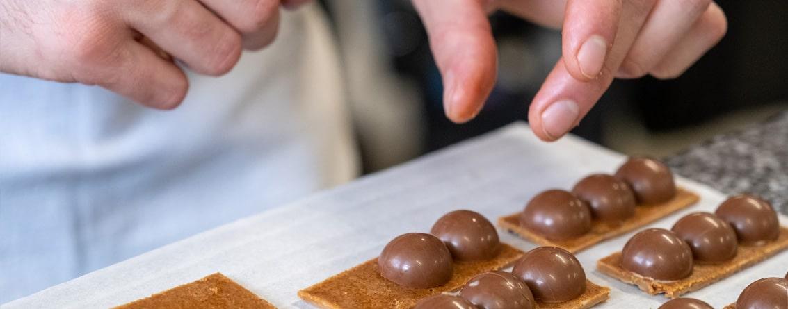 Apprenti en train de disposer des demi-sphères en chocolat sur une base de nougatine