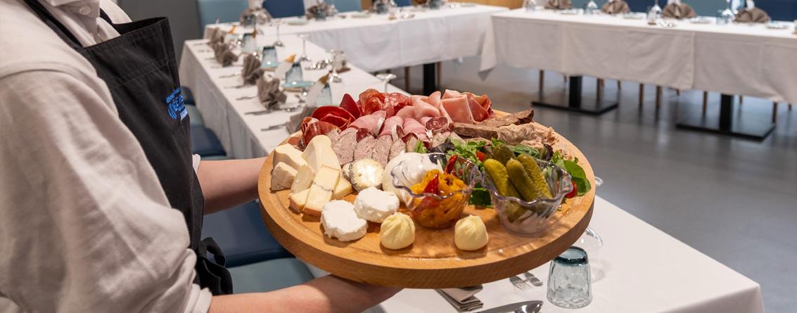 Serveur porte un plateau avec de la charcuterie et du fromage