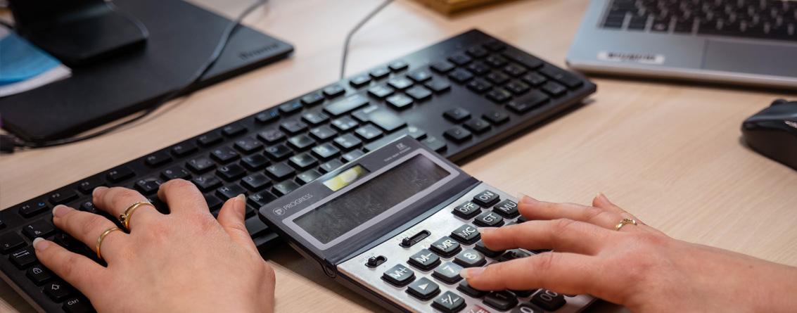 Doigts de femme sur les touches d'une calculatrice et sur le clavier d'un ordinateur