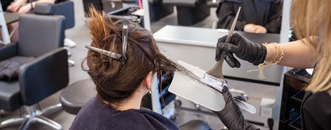 Coiffeuse appliquant une couleur à une cliente