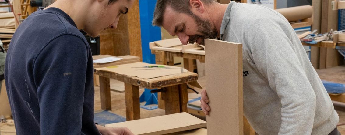Un professeur et son apprenti travaillent sur la conception d'un meuble