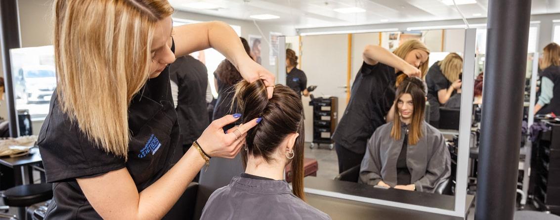 Coiffeuse en train de réaliser une coiffure à une jeune femme