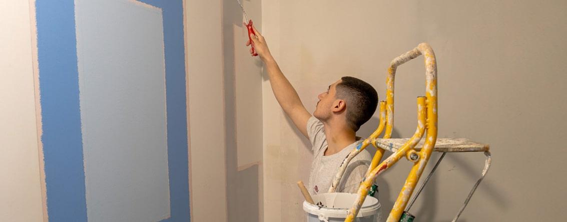 Apprenti en train de peindre un mur au rouleau