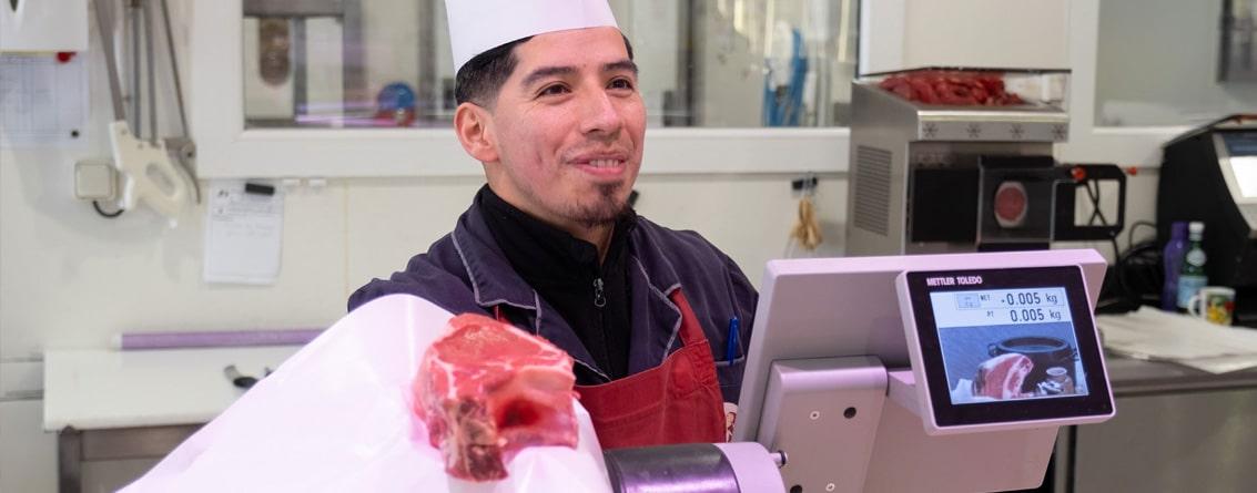 Un artisan boucher montre un morceau de viande à son client