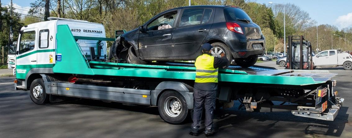 Un dépanneur installe une voiture accidentée sur son remorqueur