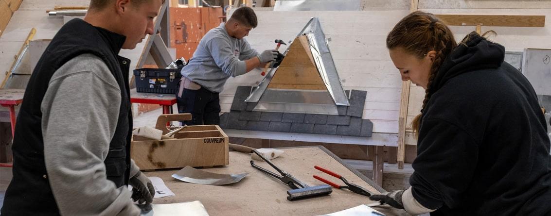 Jeunes apprentis travaillant sur des feuilles de zinc
