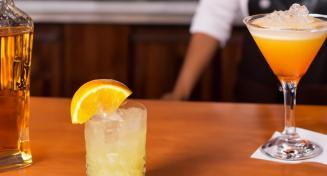 Comptoir avec des cocktails et un barman en arrière plan