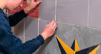 Apprenti en train de poser des croisillons entre des dalles de carrelage