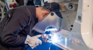 Apprenti carrossier réalisant une soudure sur la carrosserie d'une voiture