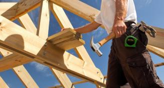 Homme sur la construction d'un toit avec des outils de charpentier