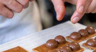 Apprenti en train de disposer des demi-sphères en chocolat sur une base de nougatine
