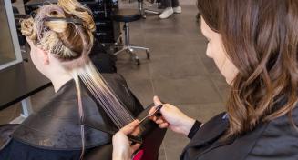 Apprenti coiffeuse mesurant une mèche de cheveux avec ses doigts ciseaux à la main