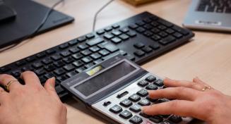 Doigts de femme sur les touches d'une calculatrice et sur le clavier d'un ordinateur