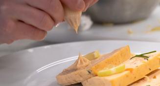 Gros plan sur un plat avec main qui dépose une noix de crème au pochoir