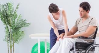 Jeune ergothérapeute en train d'échanger avec un patient en fauteuil roulant 