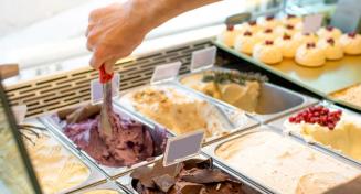 Bacs de glace au multiple parfums. Une main prépare une glace avec un portionneur