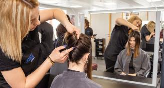 Coiffeuse en train de réaliser une coiffure à une jeune femme