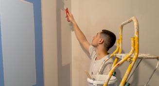 Apprenti en train de peindre un mur au rouleau