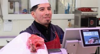 Un artisan boucher montre un morceau de viande à son client