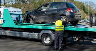 Un dépanneur installe une voiture accidentée sur son remorqueur